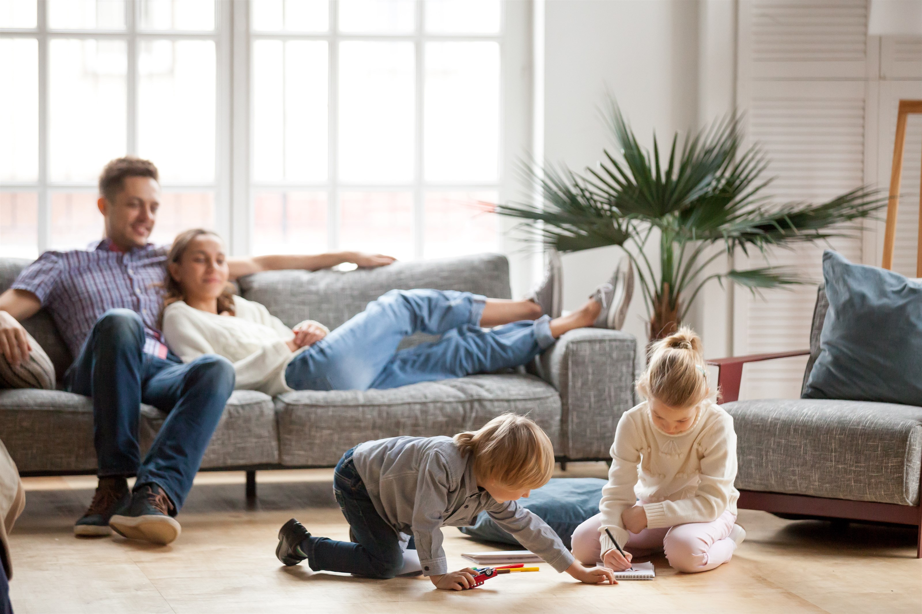 Une famille heureuse dans un salon propre et sain. Les enfants jouent au sol. Océanick Nettoyage, compagnie de nettoyage résidentiel à Québec, vous offre une tranquillité d’esprit.